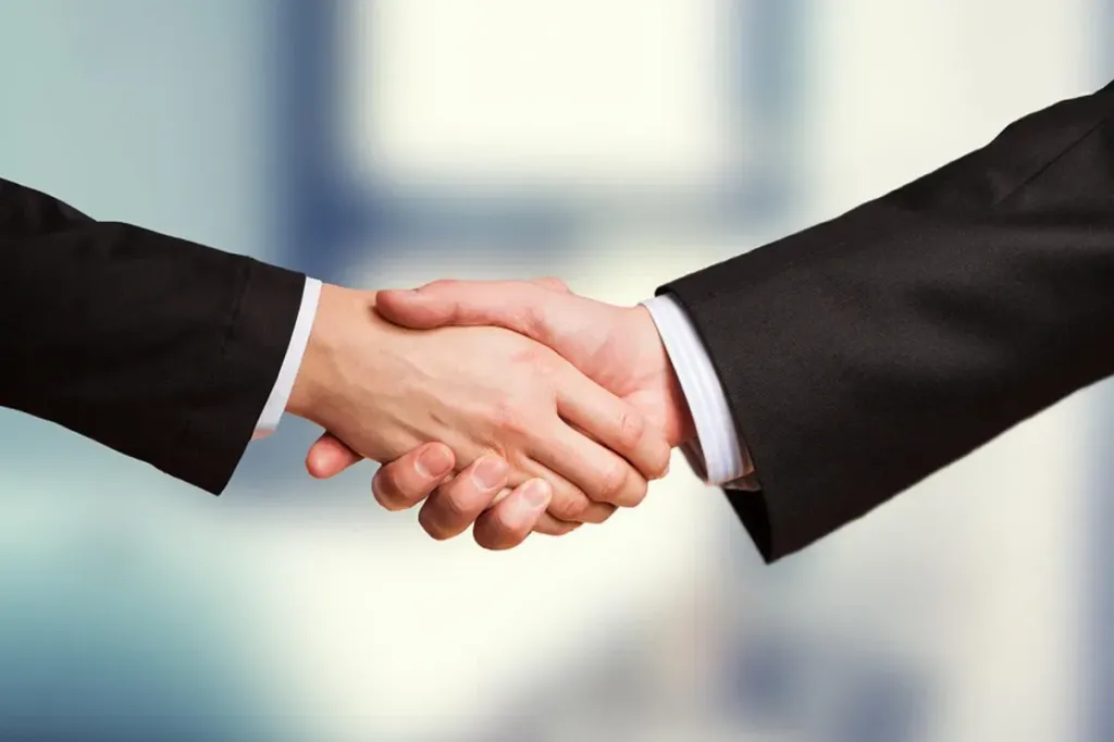 Dua rekan kerja sedang melakukan diskusi asertif dan negosiasi secara ramah di ruang meeting