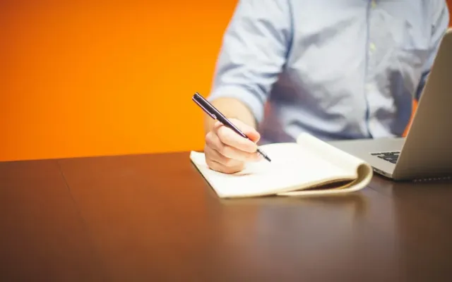 Seorang profesional berdiri percaya diri di tengah suasana kantor modern