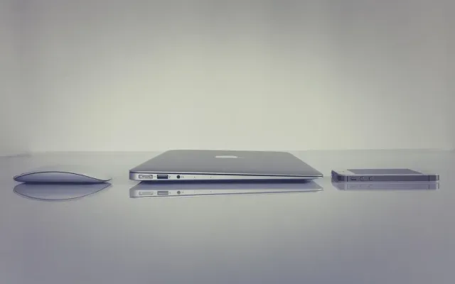 Setup meja kerja modern di rumah dengan laptop dan tanaman hias untuk mendukung produktivitas kerja hybrid