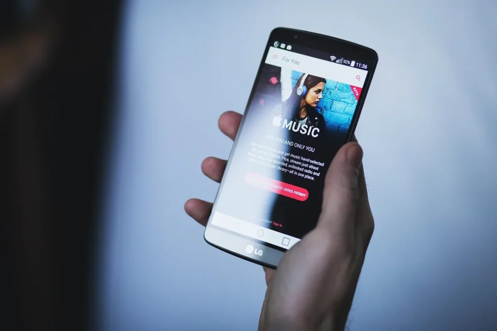 Seseorang memegang smartphone dengan tatapan lelah di dalam kamar gelap saat malam hari.