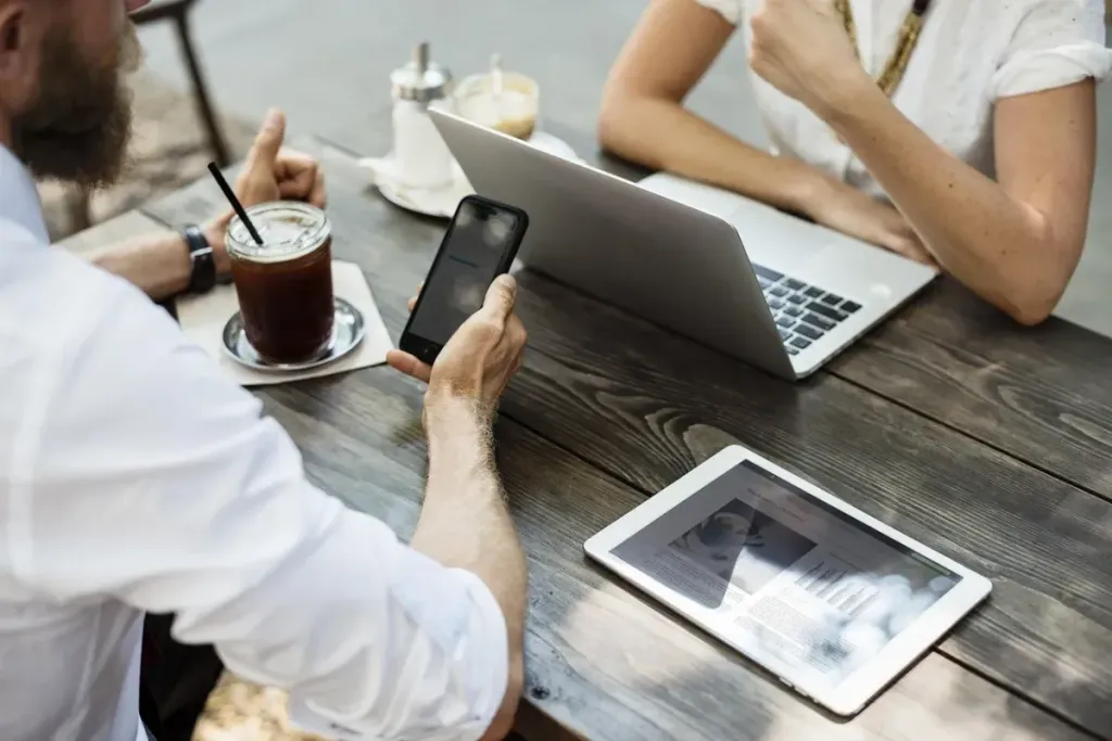 Tangan seseorang sedang mengetik di keyboard laptop di tempat yang nyaman dekat secangkir kopi.